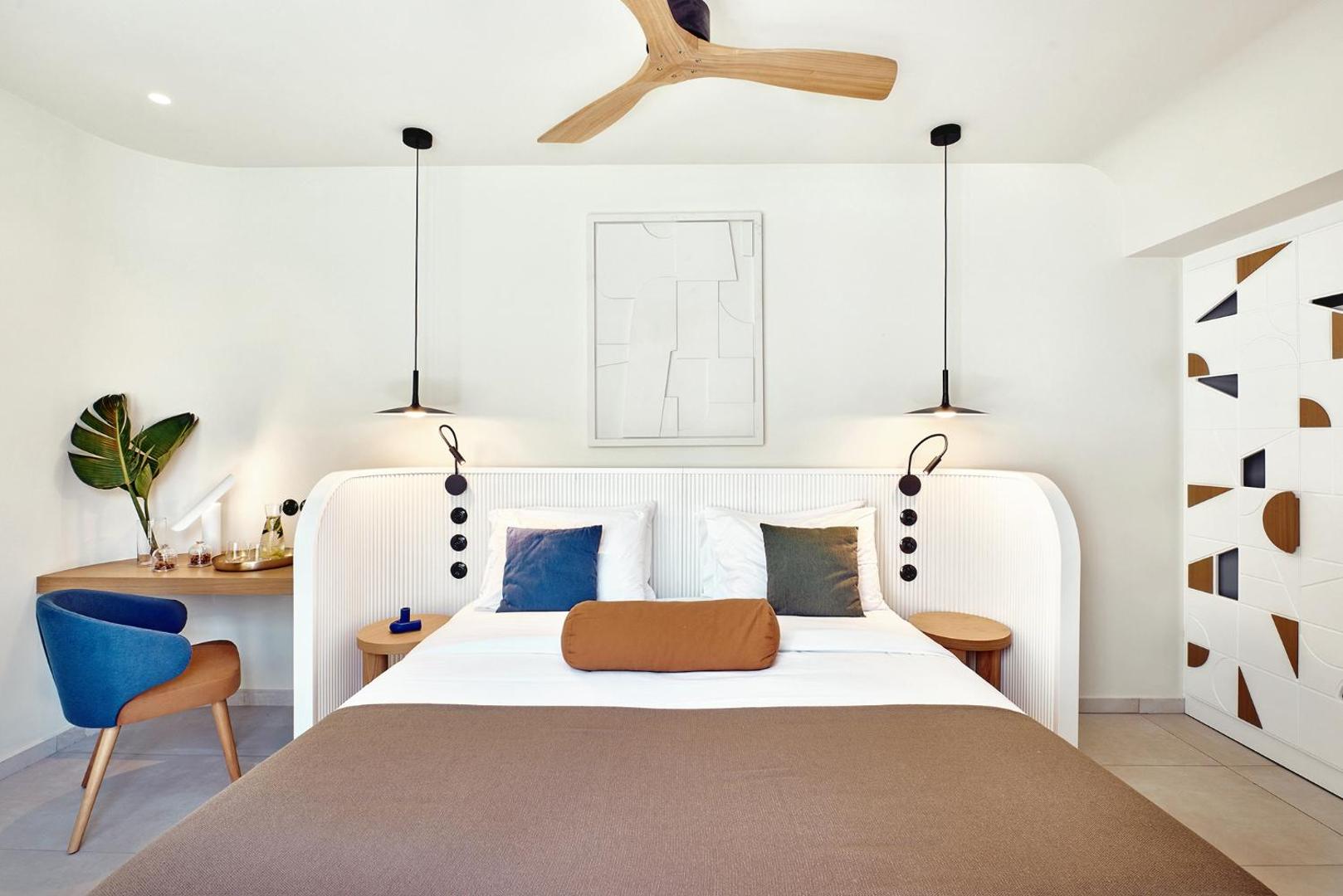 Gaišs un moderns viesnīcas numurs ar lielu gultu un minimālistisku dizainu.