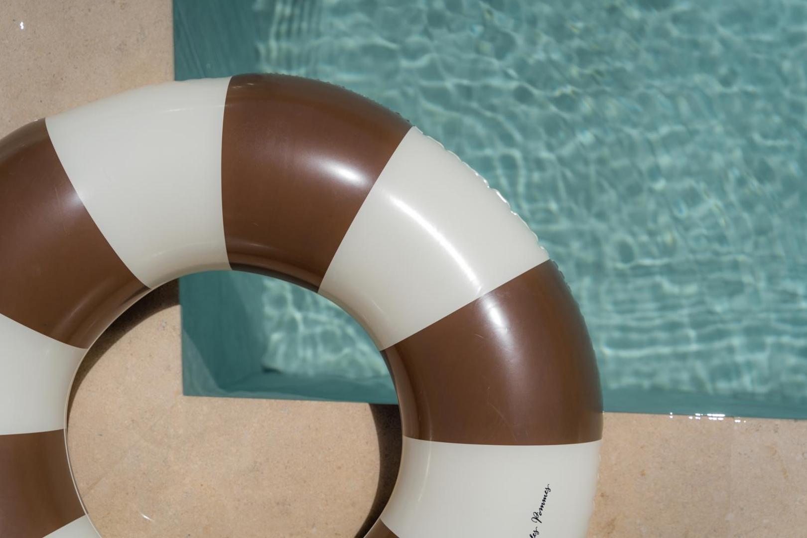 Tuvplāns ar svītrainu peldriņķi pie Elios Hill baseina dzidrā ūdens.