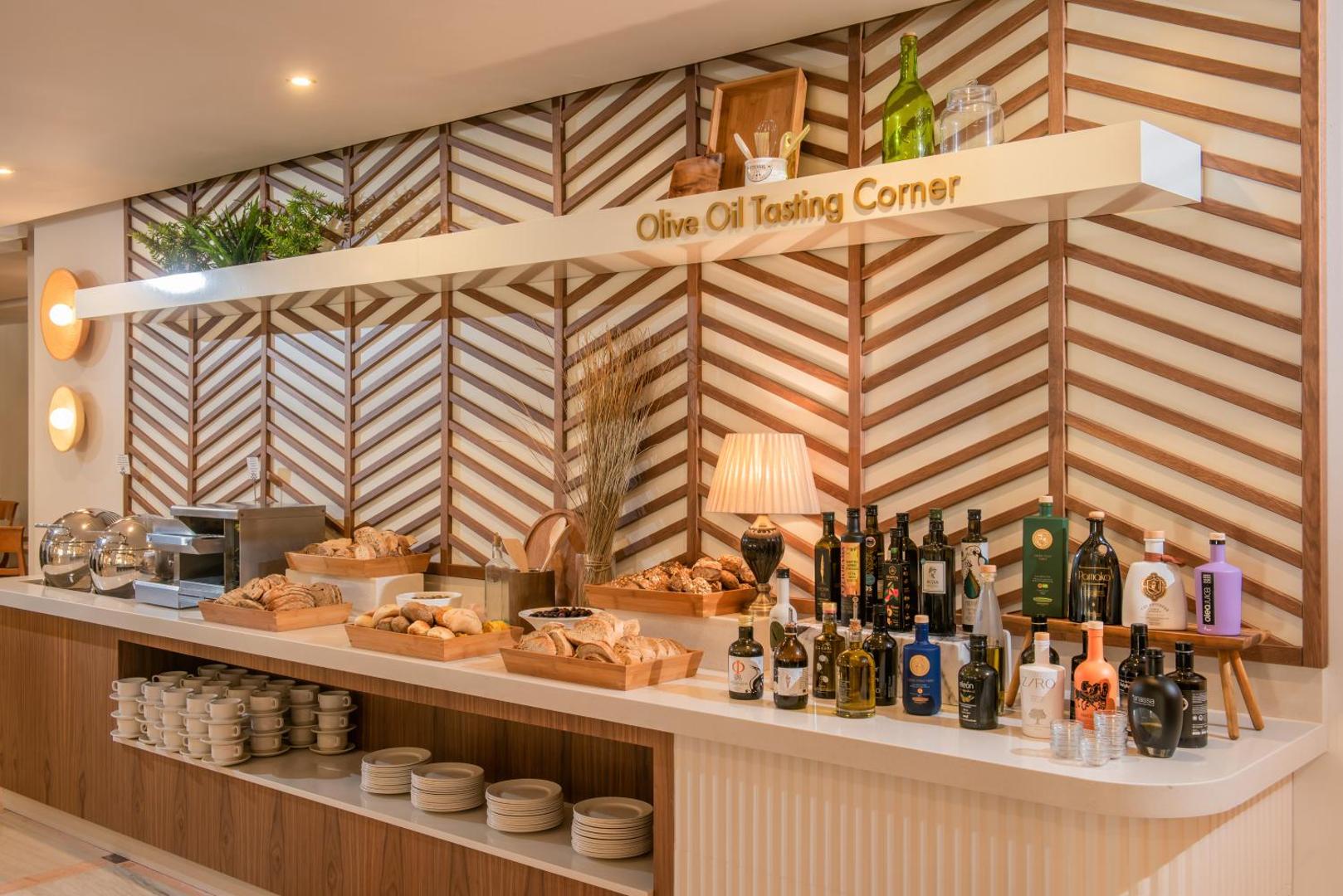 Viesnīcas Creta Royal olīveļļas degustācijas stends ar dažādām pudelēm un svaigu maizi.