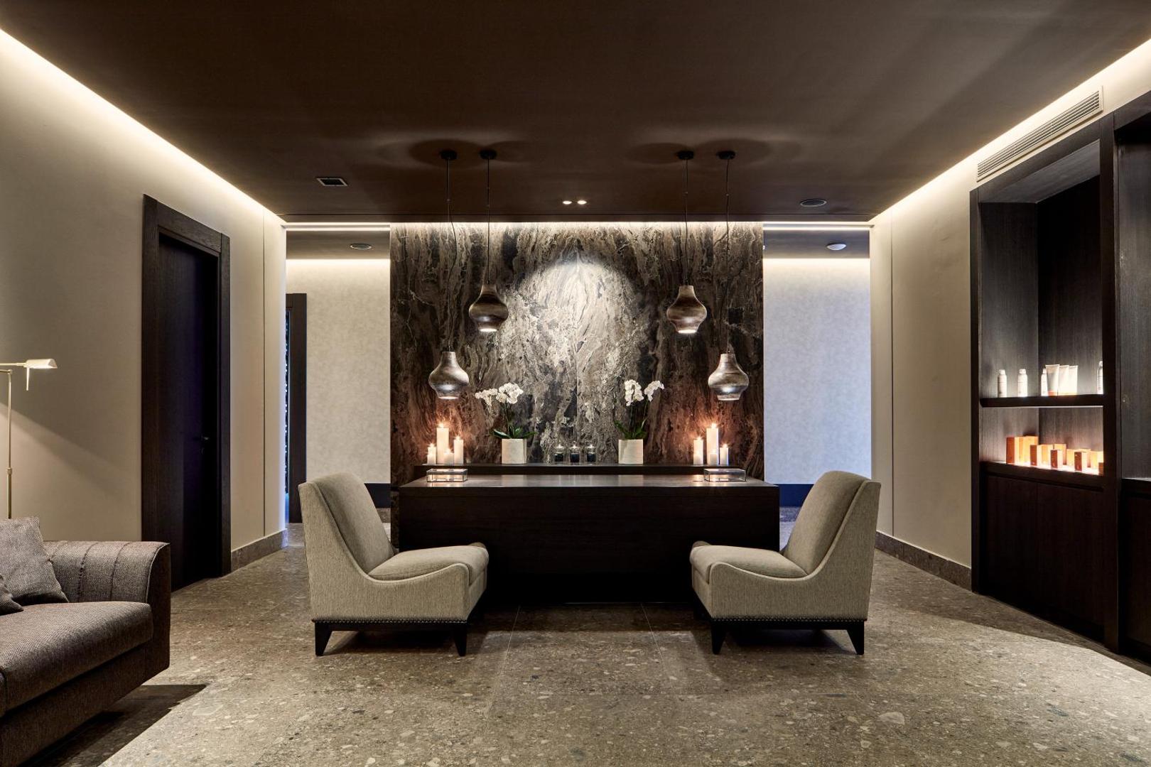 Luksusa spa zonas interjers ar tumša akmens sienu, svecēm un mīkstiem atpūtas krēsliem.