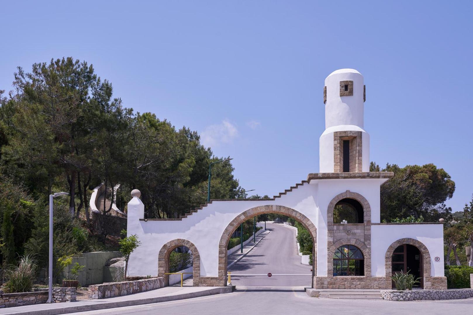 Viesnīcas iebrauktuve ar tradicionāla stila baltu arkas vārtu konstrukciju un torni.