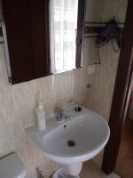 Un lavabo blanco en un baño con espejo. en Hostal Becares, en Palencia