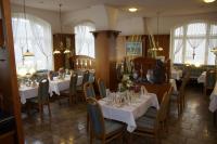 Un restaurante con mesas y sillas blancas y ventanas. en Ratskeller Thum, en Thum