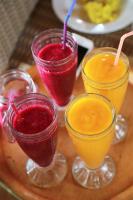 four different colored drinks in glasses on a wooden tray at Seahouse Bali Indah Beach Inn in Kuta