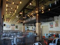 Un comedor con mesas, sillas y luces. en B&B Bela Vrba, en Bačko Novo Selo