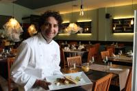 a chef holding a plate of food in a restaurant at Dependance La Mouette in Termini Imerese