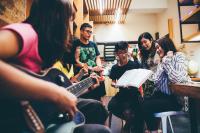 a group of people sitting in a room playing guitars at On My Way - Taipei Hostel in Taipei