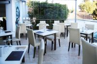a restaurant with white tables and chairs and a large window at Hotel Años 50 in Torremolinos