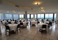a restaurant with white tables and chairs and windows at Hotel Venus in Gabicce Mare