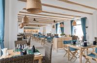 a restaurant with blue tables and chairs and windows at Risemount Premier Resort Da Nang in Da Nang