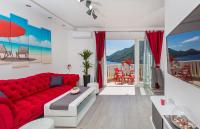 a living room with a red couch and a view of the ocean at Apartments More in Sobra