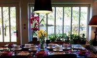 a dining room table with flowers in a room with windows at Aux Rives de Honfleur in Berville-sur-Mer