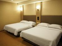 two beds in a hotel room with white sheets at The Riverside Hotel International in Kaohsiung