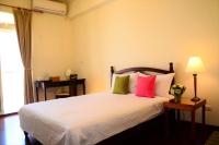 a bedroom with a bed with pink and green pillows at East of Love Homestay in Hualien City