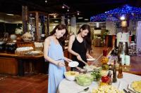 two women are preparing food at a buffet at Rainbow Resort Hotel in Wenquan