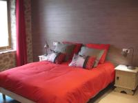 a bed with red sheets and pillows in a bedroom at Maison Chabrat in Liginiac