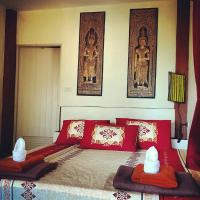 a bedroom with a bed with red pillows and pictures on the wall at Moonstone Studio in Haad Rin