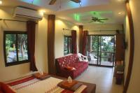a living room with a red couch and some windows at Moonstone Studio in Haad Rin