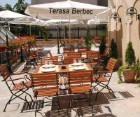 um restaurante com mesas e cadeiras de madeira e guarda-sóis em Hotel Central em Ploieşti