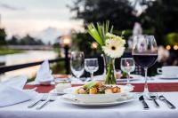 een tafel met een bord eten en wijnglazen bij Aruntara Riverside Boutique Hotel in Chiang Mai