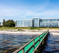 a building on the beach next to a body of water at Storebælt Sinatur Hotel &amp; Konference in Nyborg