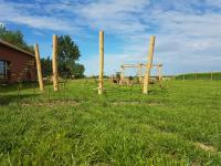 a row of wooden poles in a field with a playground at Holiday home Het Zeugekot in Beveren