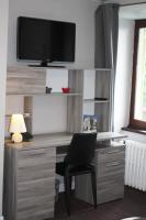 a desk with a chair and a television on a wall at Hôtel des Chazes in Saint-Jacques-des-Blats