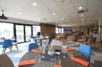 Un comedor con mesas y sillas y ventanas. en The Originals City, Hôtel de la Confluence, Agen Ouest, en Damazan