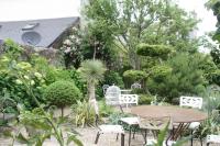 a patio with a table and chairs in a garden at Logis Saint-Léonard in Honfleur