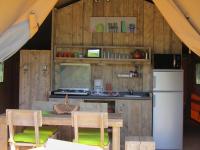 a kitchen in a tent with a table and a refrigerator at Gites Le Clos de Saires in Saires
