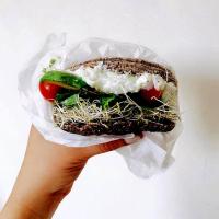 a hand holding a sandwich in a plastic wrapper at Cinco Hotel B&B in San Salvador