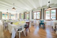 ウンゼレ・リーベにあるZum Hirschen Boutique Hotel Val di Nonの白いテーブルと椅子と窓のあるレストラン