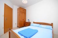 a bedroom with a bed and a wooden cabinet at Apartments Branislav in Rogoznica