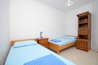 a twin bedroom with two beds and a cabinet at Apartments Branislav in Rogoznica