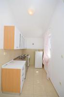 a kitchen with white cabinets and a white refrigerator at Apartments Branislav in Rogoznica