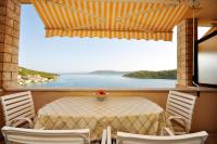 a table with chairs and a view of the ocean at Apartments Val in Vinišće