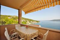 a table on a balcony with a view of the water at Apartments Val in Vinišće