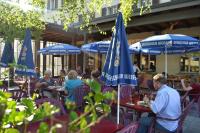a group of people sitting at tables with umbrellas at Hotel Des Alpes - Restaurant & Pizzeria in Airolo