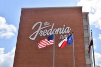 una señal de hotel en el lateral de un edificio con dos banderas en The Fredonia Hotel, en Nacogdoches