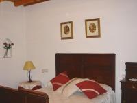 a bedroom with a bed and two pictures on the wall at Apartamentos Buganvilla in Villaluenga del Rosario