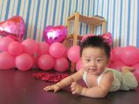 a baby laying on the floor in front of balloons at Light Blue Hostel in Hengchun South Gate
