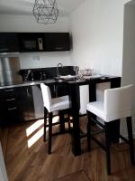 a kitchen with a black table and white chairs at La Pause Romantique in Dole