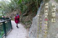 a woman walking down a path next to a rock with writing on it at Dongpo Ti Lun Hotel in Xinyi