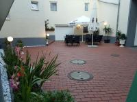 a patio with tables and chairs and an umbrella at Hotel Restaurant Rhodos in Elsterwerda