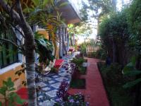 un jardín con un camino con flores y un árbol en Hotel y Restaurante Playa Linda, en San Pedro La Laguna