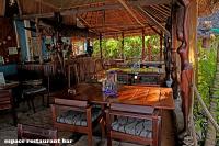 un restaurante con mesa de madera y sillas en Chez Yolande, en Ampangorinana
