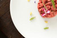 Un plato de carne con flores sobre una mesa. en Locanda La Raia, en Gavi