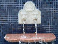 a water fountain with two lion heads on a blue tiled wall at Pousada Boulevard in Cabo Frio