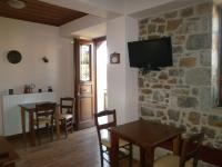 a living room with a table and a tv on a stone wall at Thea Valtessinikou in Valtessiniko