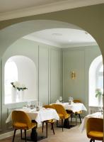 Un comedor con mesas blancas y sillas amarillas. en Das Tegernsee, en Tegernsee